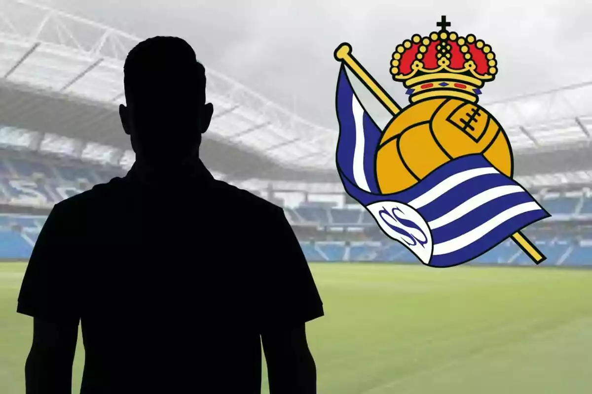 Silueta de una persona frente a un estadio de fútbol con el escudo de la Real Sociedad en el fondo.