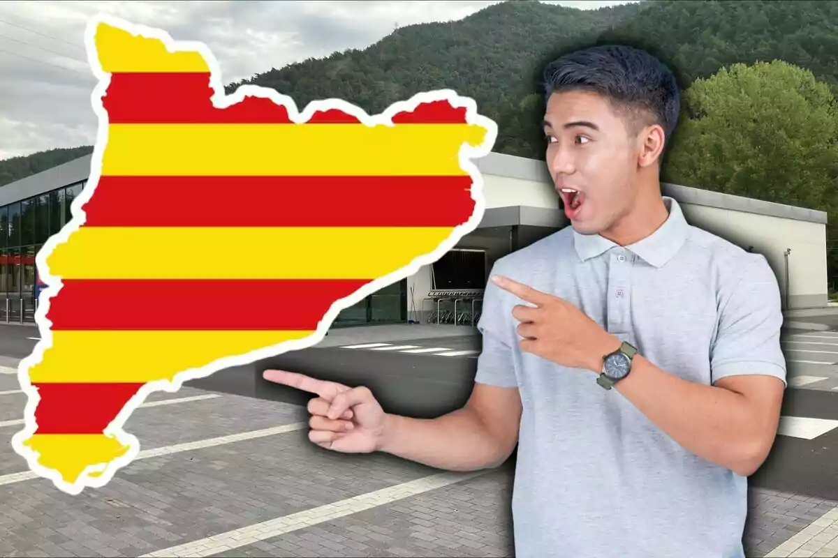 Home sorprès assenyalant un mapa de Catalunya amb els colors de la bandera catalana davant d’un edifici modern i amb muntanyes de fons