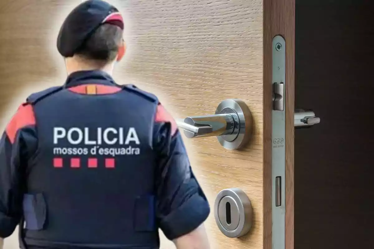 Un agent dels Mossos d'Esquadra d'esquena al costat d'una porta entreoberta amb un pany modern.