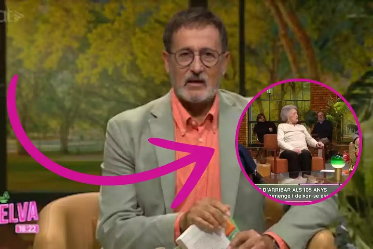 Un presentador de televisión con gafas y barba está hablando en un programa, mientras sostiene un libro; hay un círculo rosa que destaca a una mujer mayor sentada en el set.