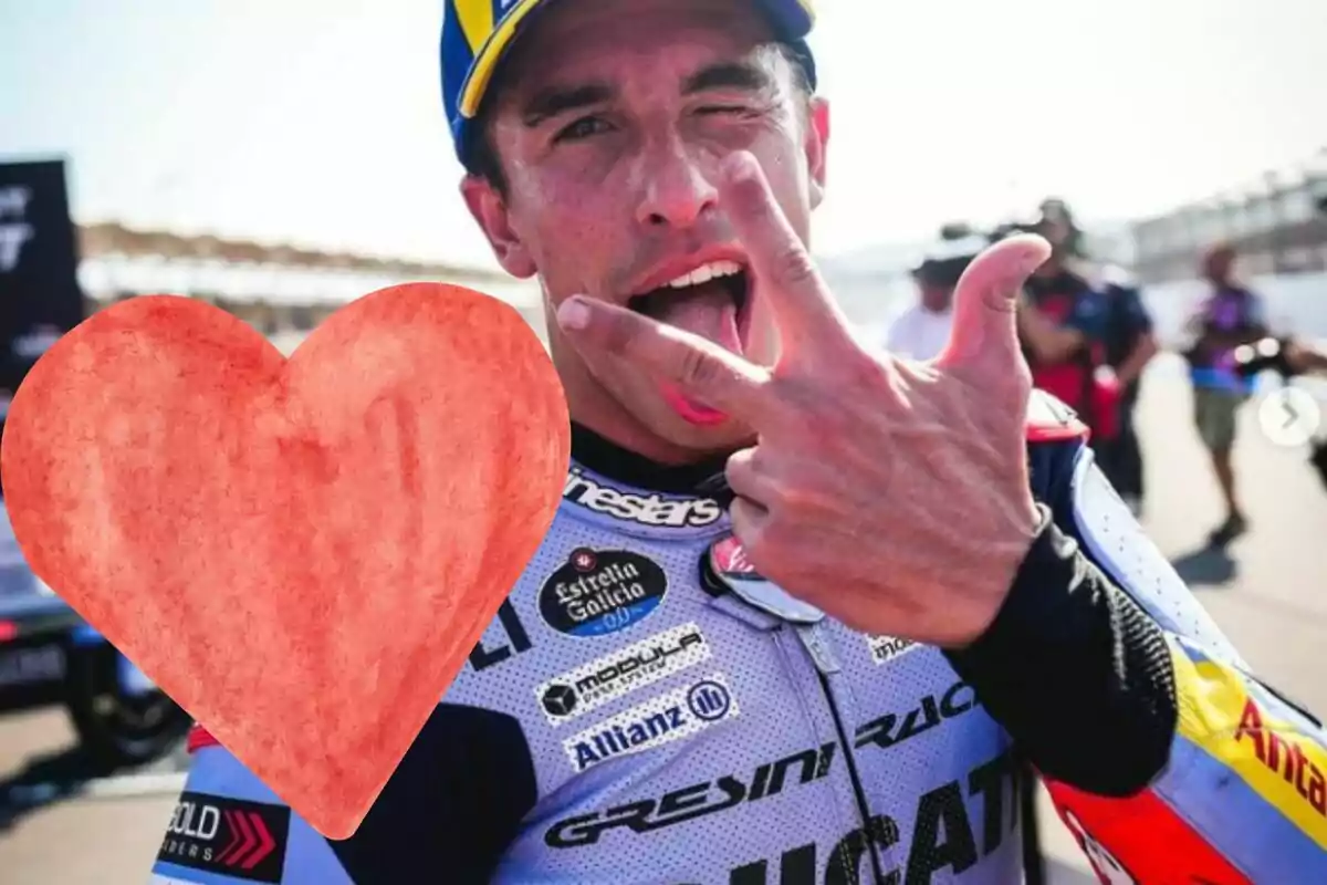 Pilot de motociclisme amb casc i uniforme fent un gest amb la mà i traient la llengua, amb un cor vermell dibuixat al pit