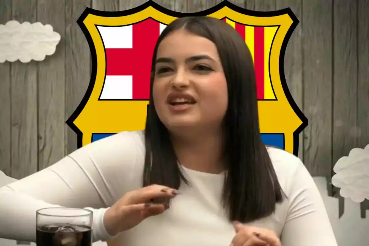 Una persona amb cabell fosc i una samarreta blanca està asseguda davant d'un fons amb l'escut del FC Barcelona.