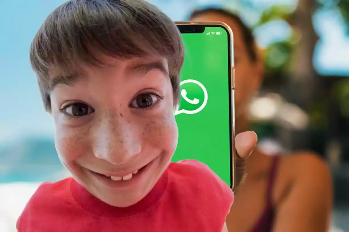 Un nen somrient amb pigues està davant d'un telèfon que mostra el logotip de WhatsApp.