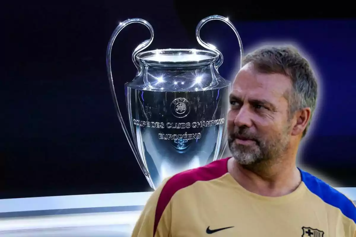 Hombre con camiseta de fútbol junto a un trofeo de la UEFA Champions League.