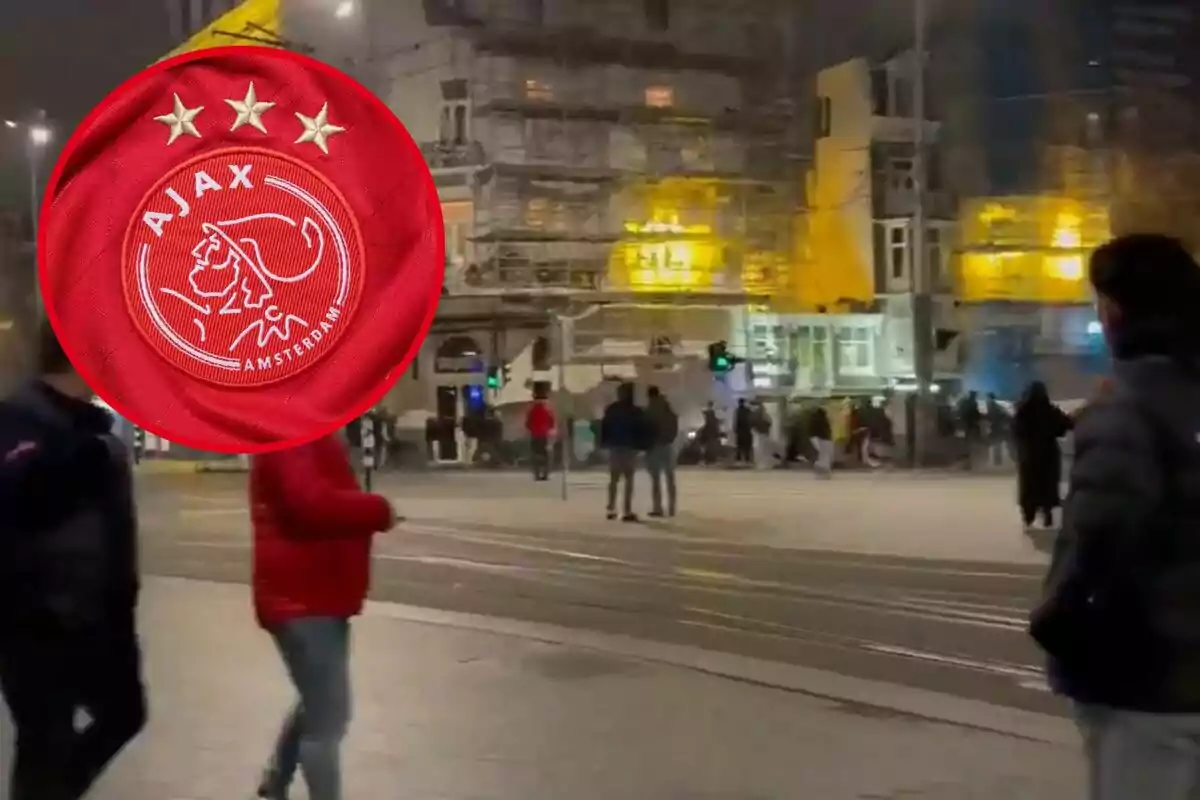 Una escena nocturna en una ciudad con personas caminando por la calle y un emblema del Ajax superpuesto.