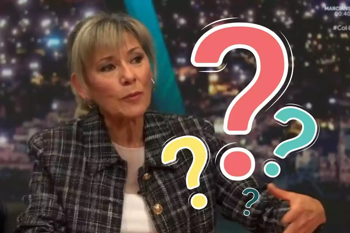 Dona de cabell ros curt amb expressió pensativa asseguda en un estudi de televisió amb signes d'interrogació de colors superposats