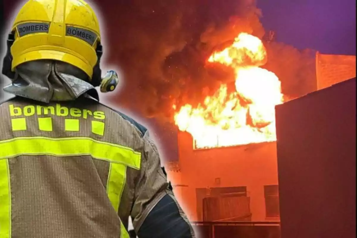 Un bombero con casco amarillo observa un edificio en llamas durante un incendio.