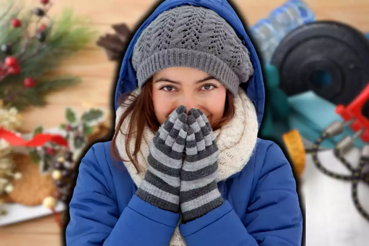 Una persona abrigada con gorro y guantes sonríe mientras se cubre la cara con las manos en un entorno invernal.