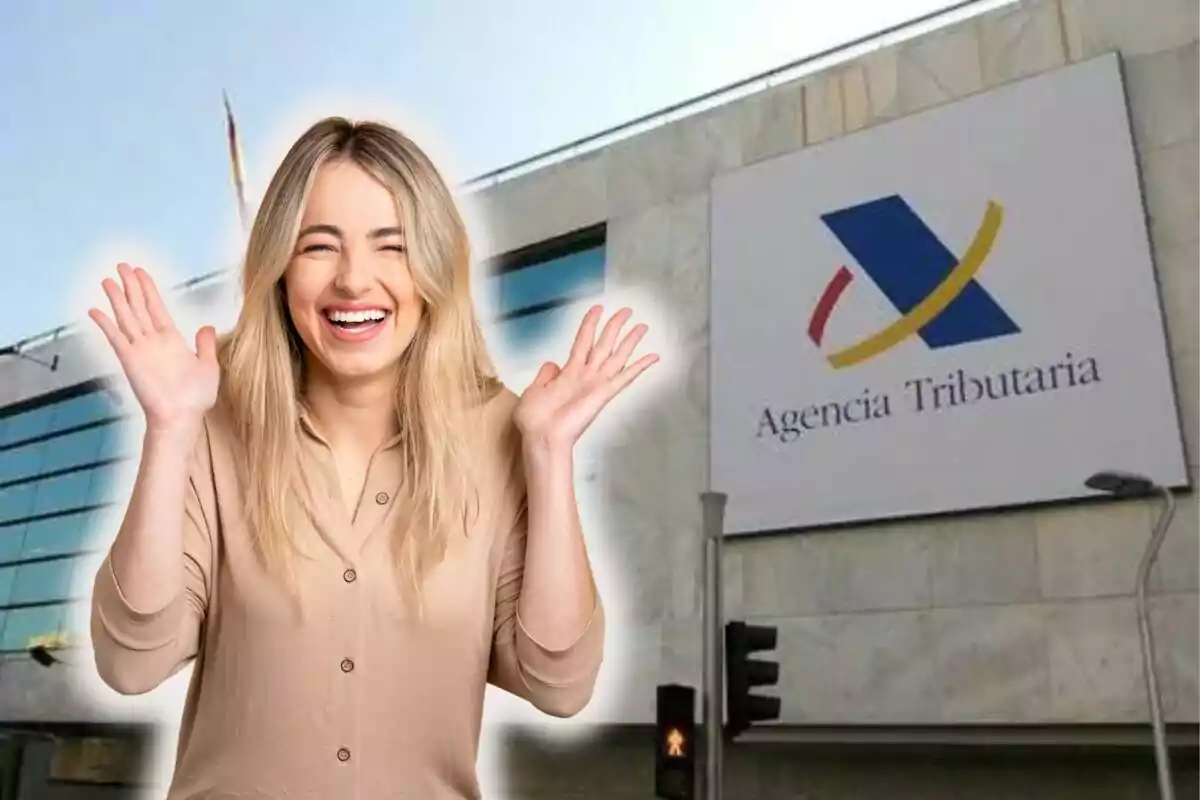 Una mujer sonriente con las manos levantadas frente a un edificio de la Agencia Tributaria.