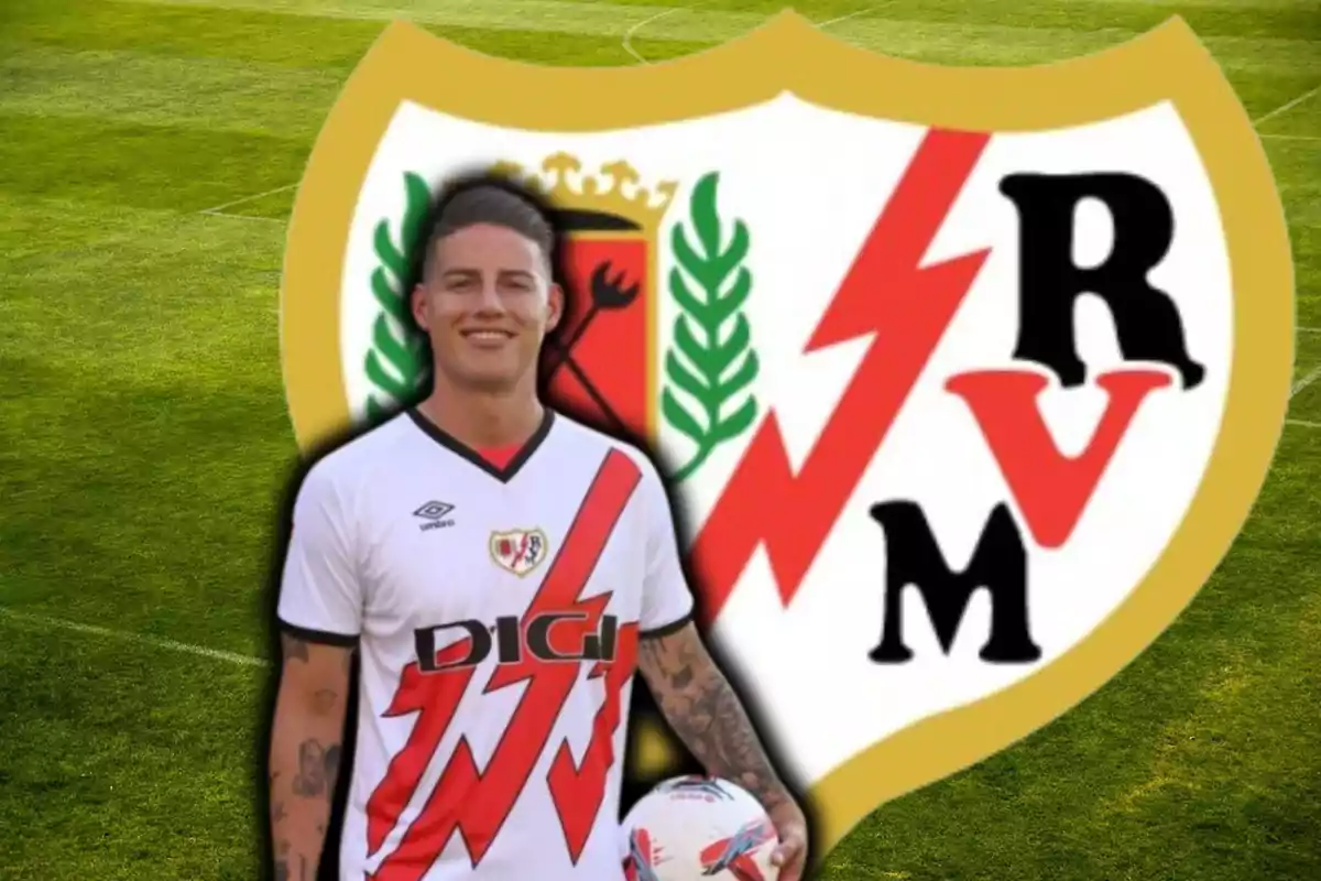 Un jugador de fútbol con el uniforme del Rayo Vallecano sostiene un balón frente al escudo del equipo en un campo de fútbol.