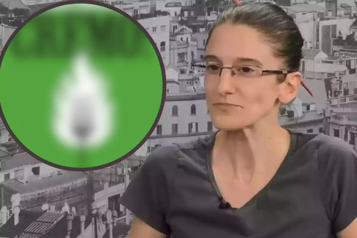 Una persona con gafas y cabello recogido está sentada frente a un fondo de edificios en blanco y negro, con un círculo verde borroso a la izquierda.