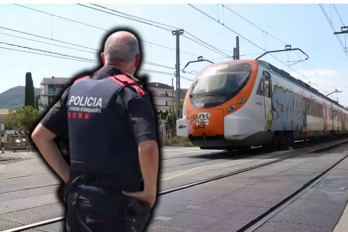 Un agent de policia observa un tren que passa per una cruïlla ferroviària.