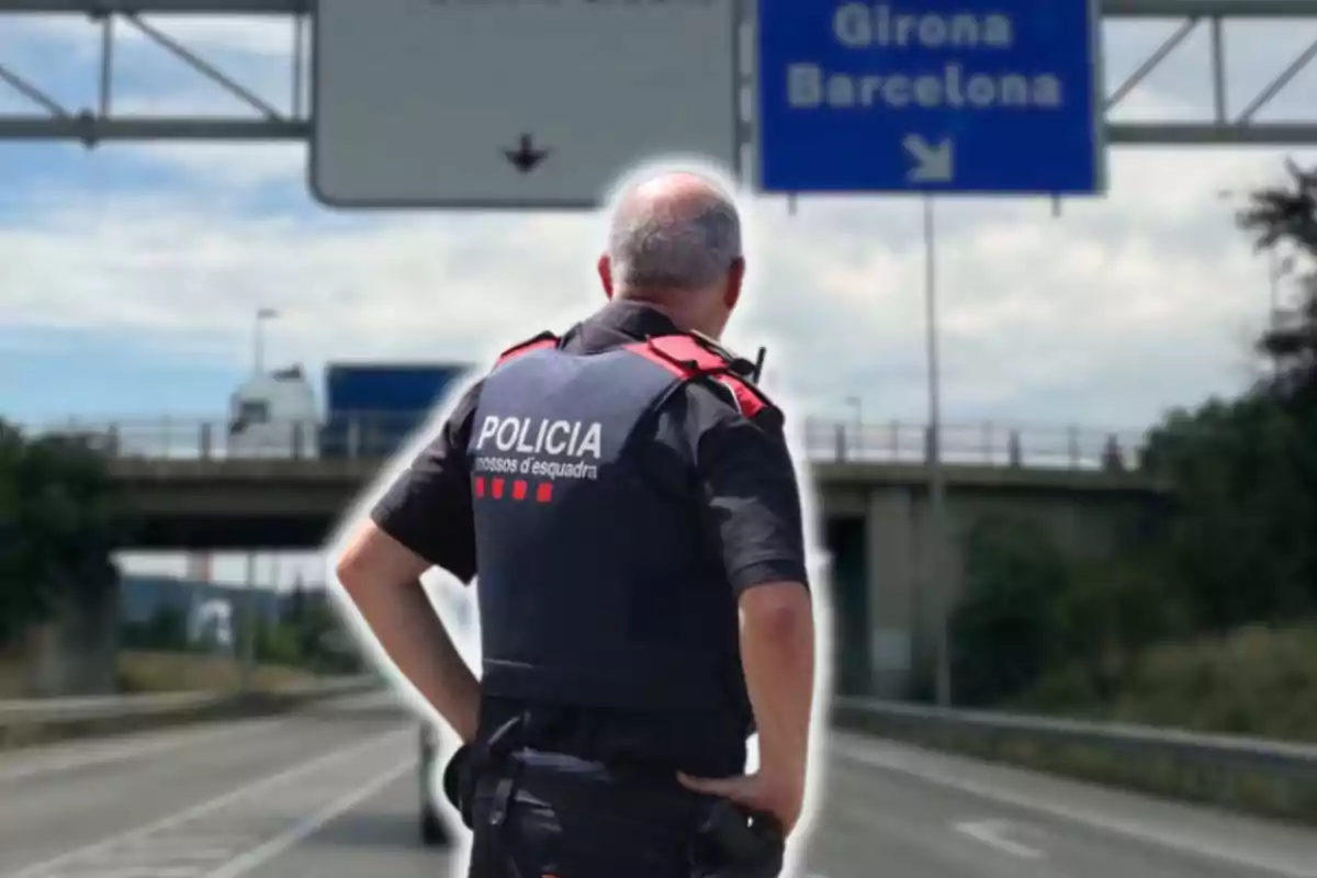 Un agente de policía de espaldas en una carretera con señales hacia Girona y Barcelona.