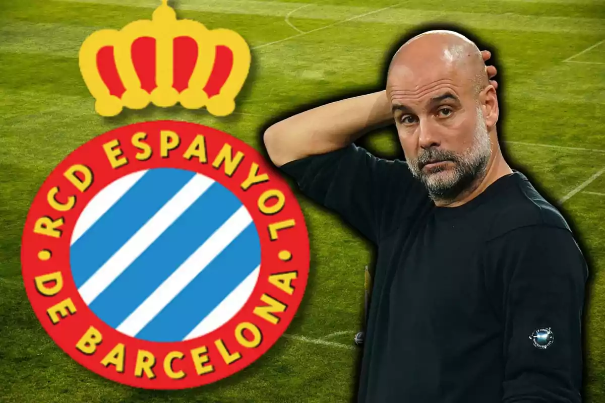 Un hombre calvo con barba y camiseta negra está junto al escudo del RCD Espanyol de Barcelona sobre un campo de fútbol.