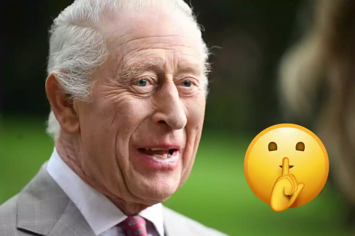 Carlos III in a suit smiles while a silence emoji appears next to him.