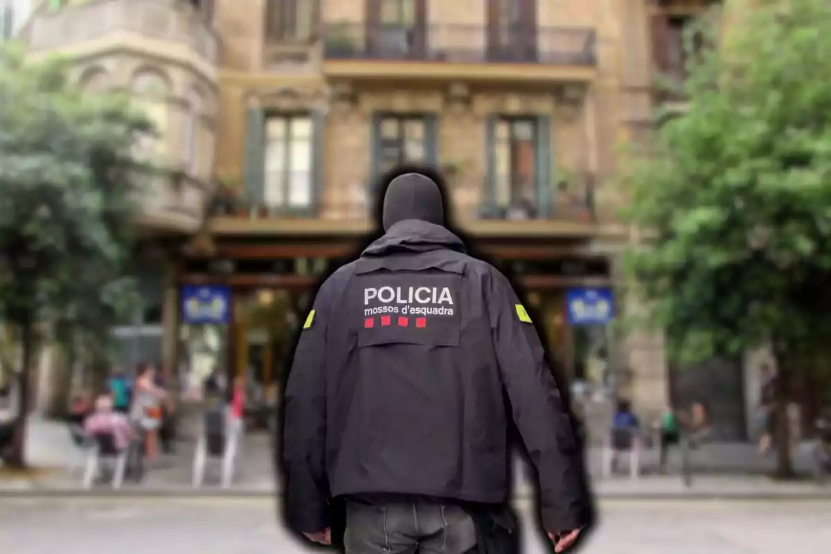 Un agente de policía de espaldas con una chaqueta que dice "Policia Mossos d'Esquadra" en un entorno urbano.