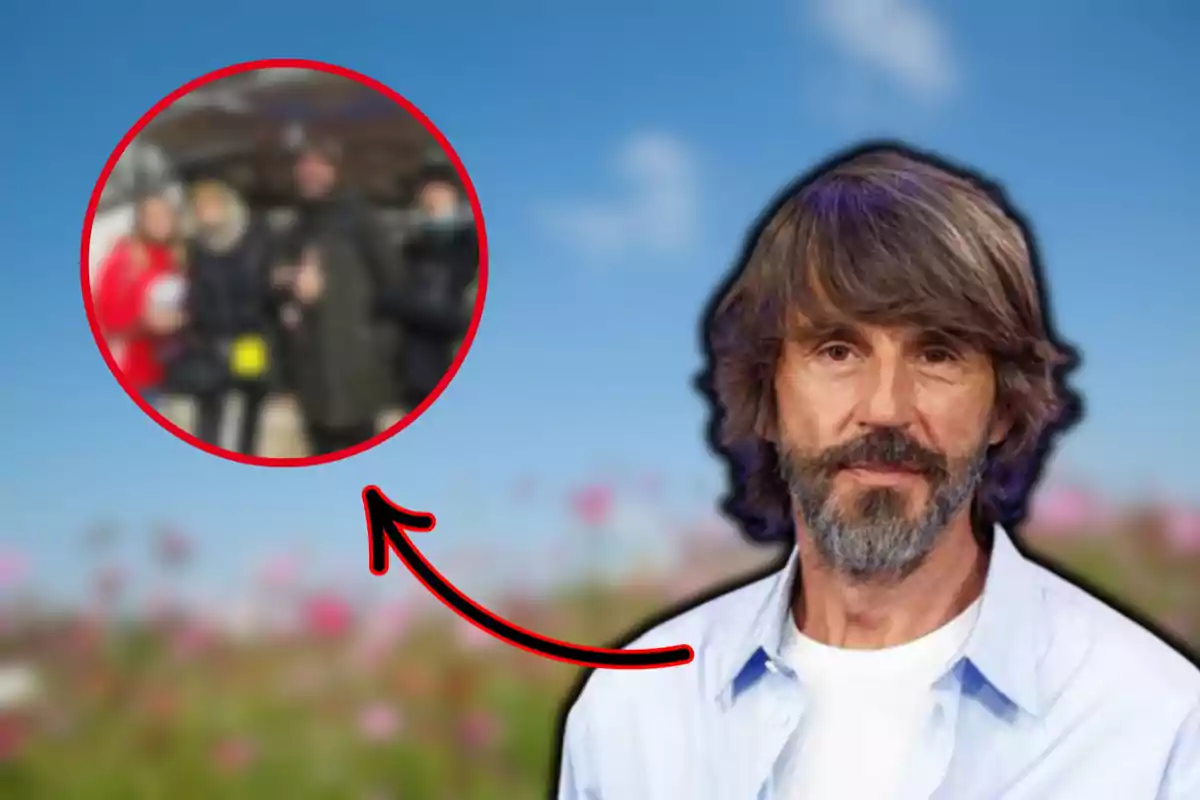 Un hombre con barba y cabello largo está en primer plano sobre un fondo de cielo azul y flores, mientras un círculo rojo con una flecha señala a un grupo de personas desenfocadas en el fondo.