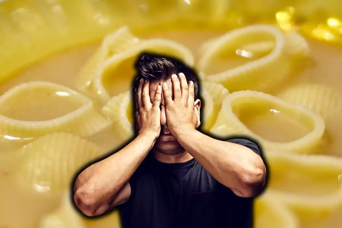 Un hombre cubriéndose el rostro con las manos sobre un fondo de sopa con pasta.