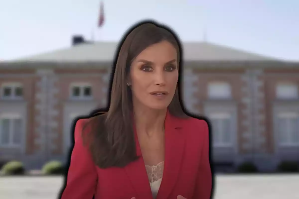 Mujer con chaqueta roja frente a un edificio borroso.