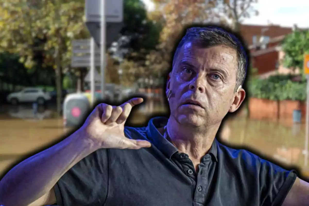 Un hombre con expresión seria y gesto con la mano frente a un fondo de una calle inundada.