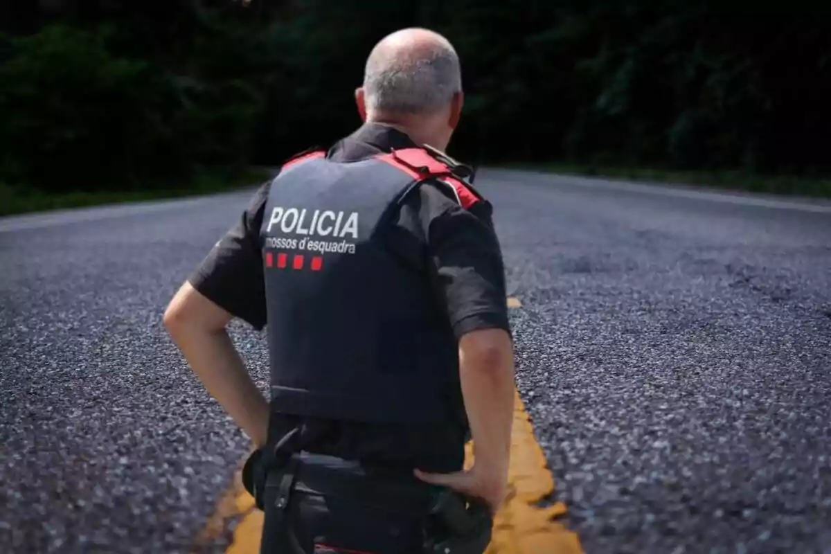 Un agente de policía de espaldas en una carretera.