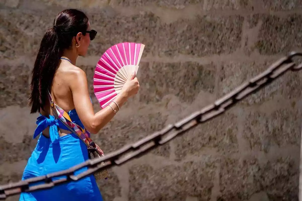 Una mujer pasando mucho calor por Sevilla con un abanico Una mujer pasando mucho calor por Sevilla con un abanico