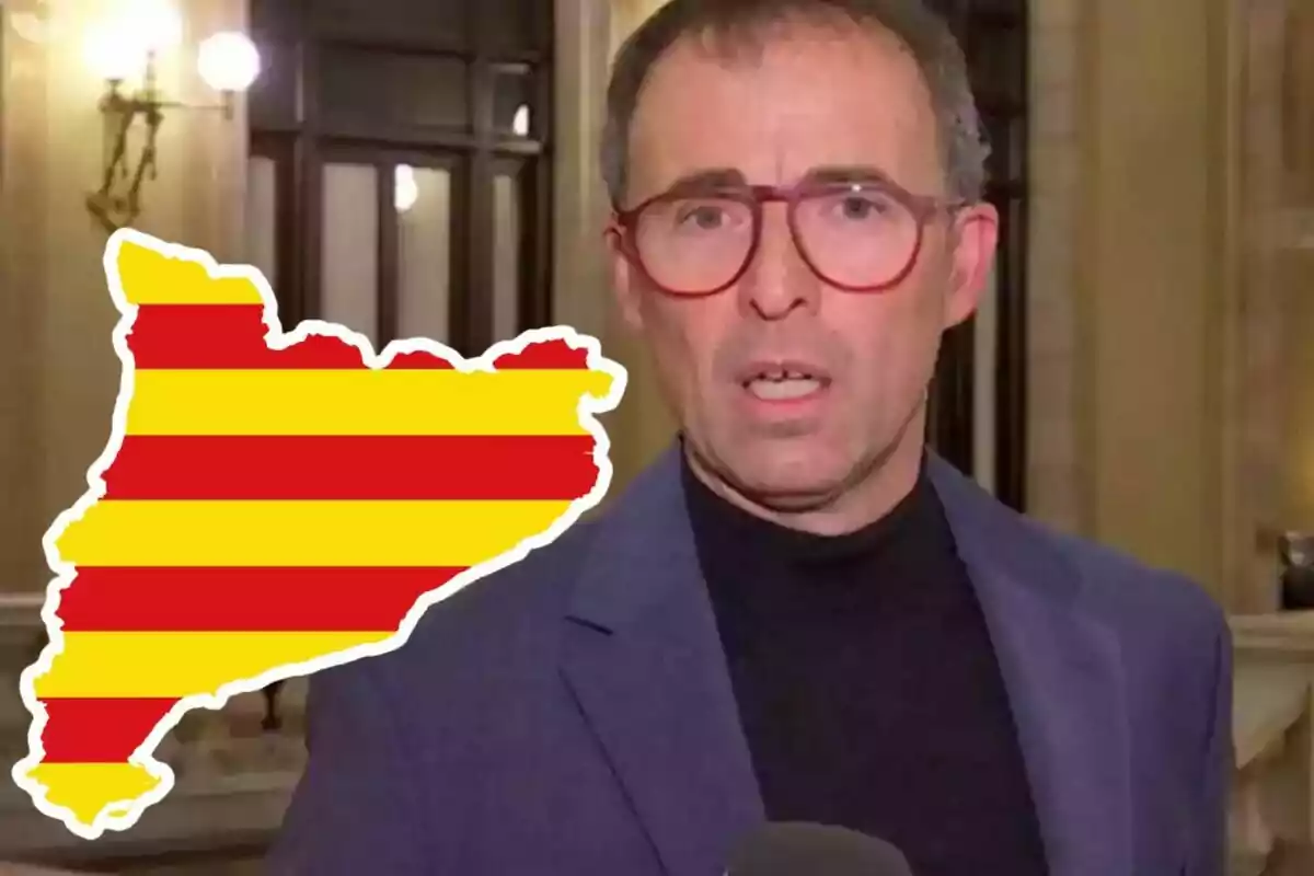 Home amb ulleres vermelles i jaqueta blava parlant davant d’una càmera amb un gràfic del mapa de Catalunya amb franges vermelles i grogues al seu costat