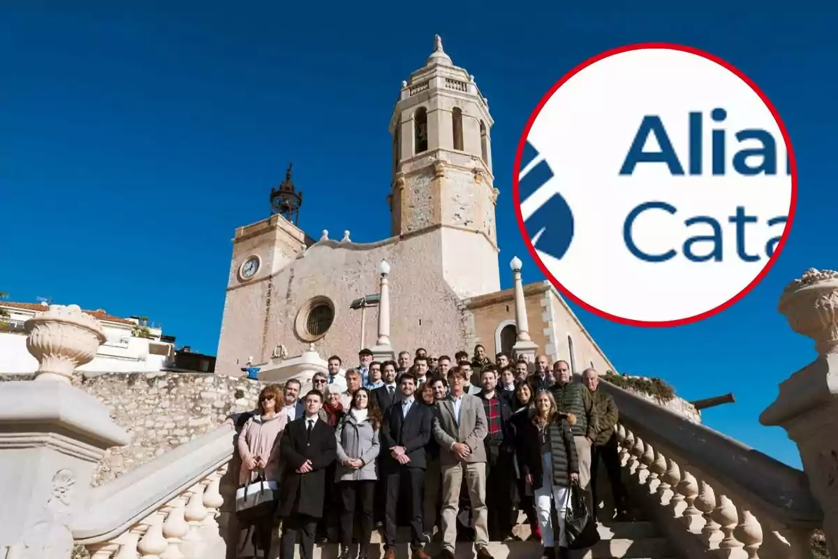 Un grup de persones posant a les escales davant d'una església amb un cel blau clar i un logotip ampliat a la cantonada superior dreta.