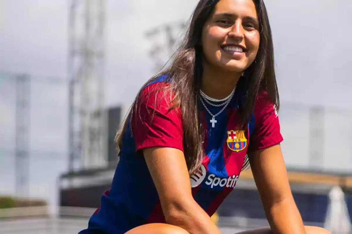Una dona amb samarreta del FC Barcelona somriu a l'aire lliure. Una dona amb samarreta del FC Barcelona somriu a l'aire lliure.