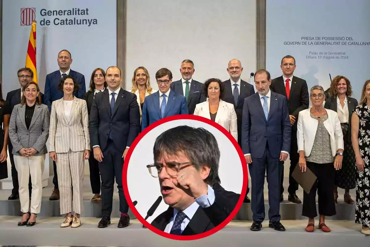 Un grup de persones posant en un escenari un cartell de la Generalitat de Catalunya i una bandera catalana, amb una imatge circular d'un home parlant en primer pla.