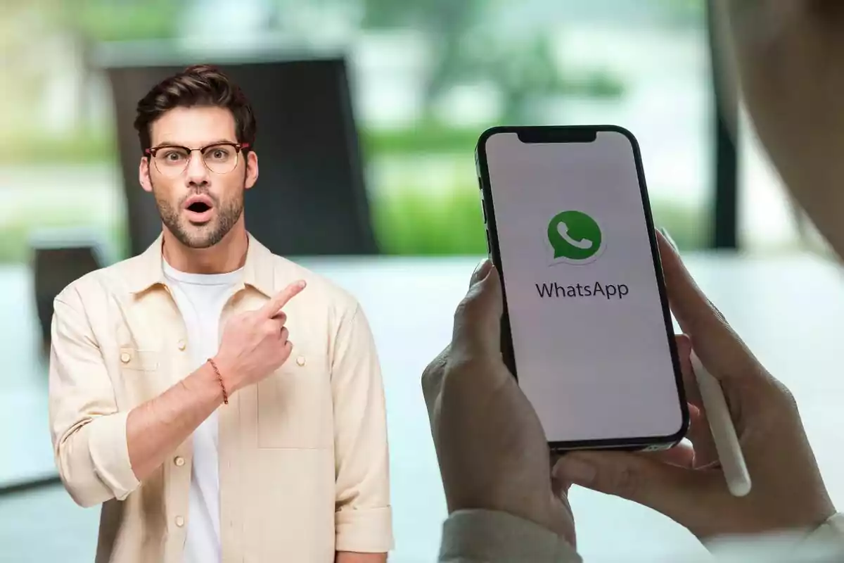 Un home amb expressió de sorpresa i assenyalant cap a un telèfon mòbil que mostra la pantalla inicial de WhatsApp.