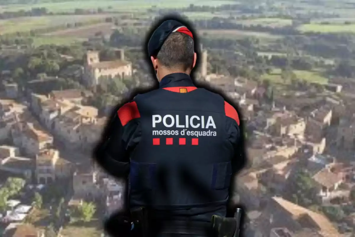Un agent dels Mossos d'Esquadra d'esquena observa un poble des d'una vista aèria
