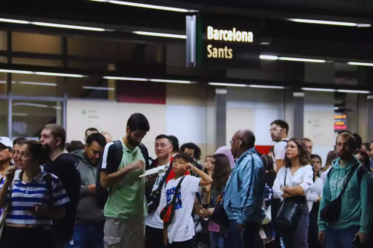 Personas esperando en la estación de tren de Barcelona Sants.