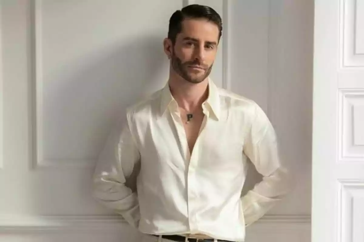 Home amb camisa blanca posant davant d'una paret blanca.