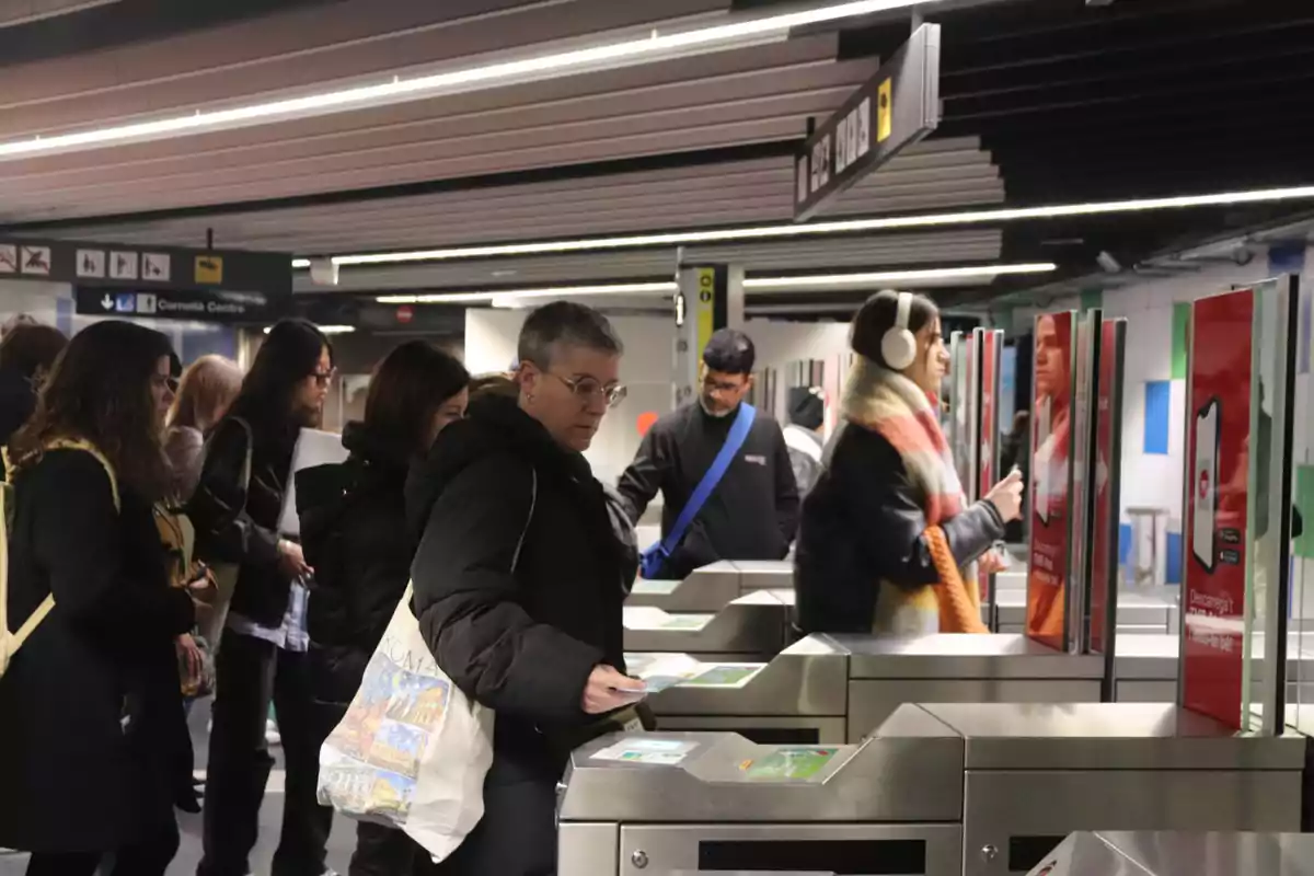 Personas pasando por torniquetes en una estación de metro.