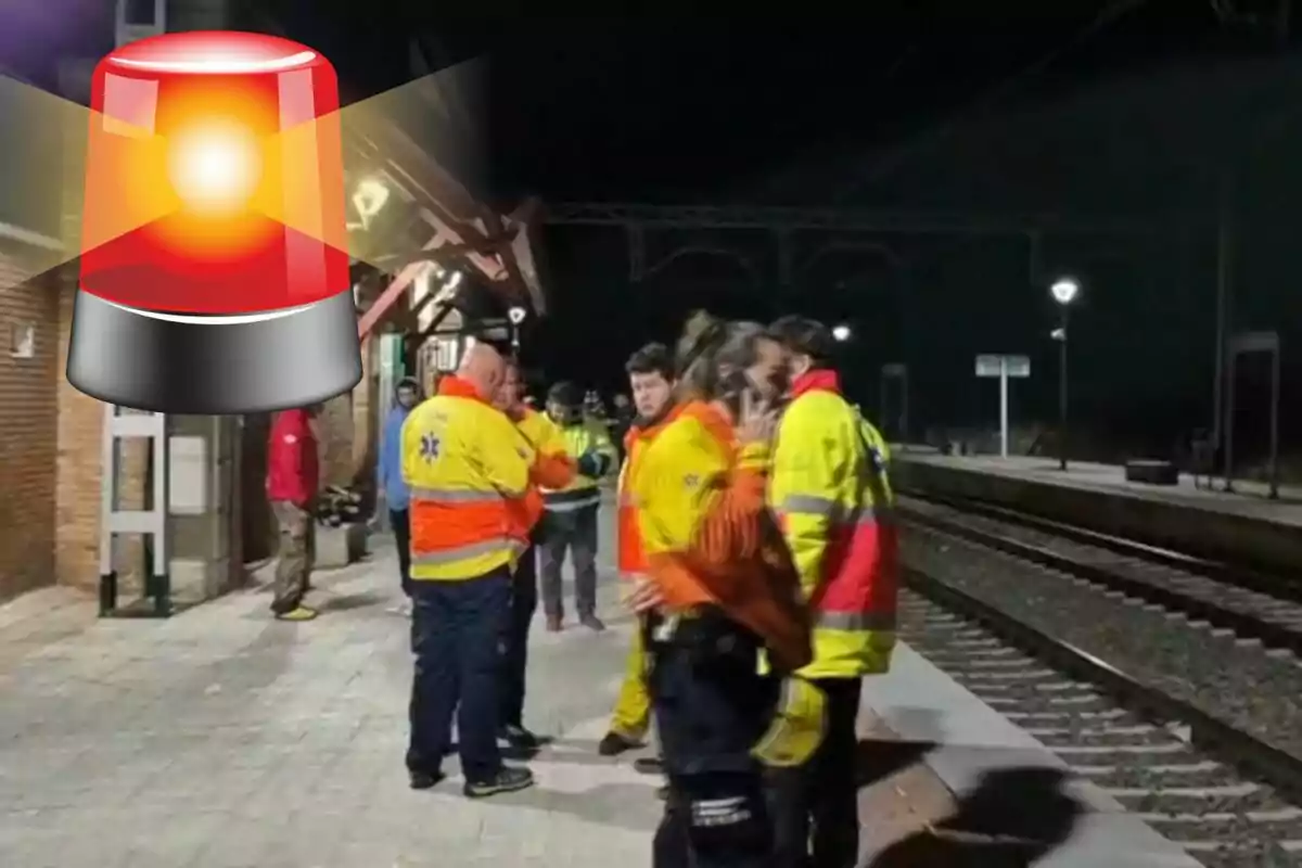 Personas con chaquetas reflectantes en una estación de tren por la noche, con un icono de sirena roja superpuesto.