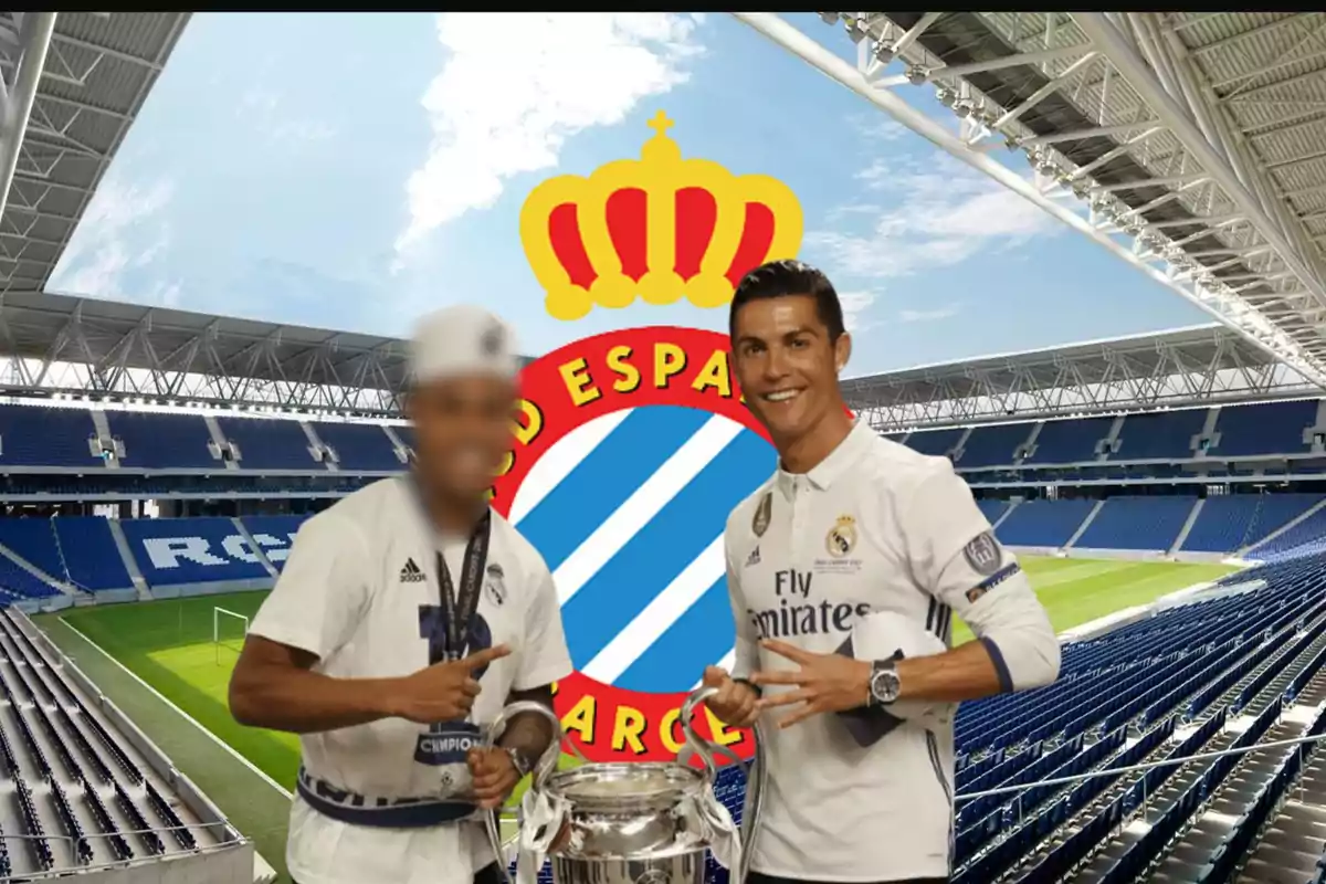 Dos jugadores de fútbol posan con un trofeo en un estadio con el escudo del Real Madrid de fondo.