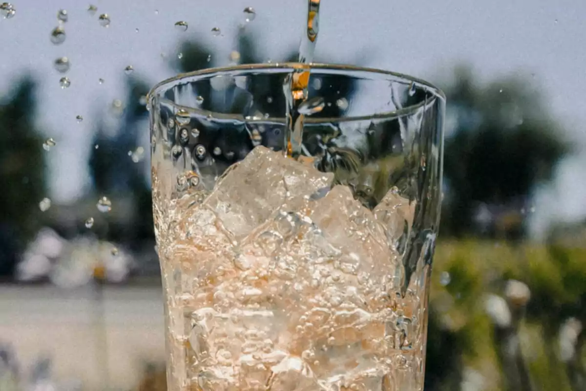 Vas de vidre amb gel mentre s’hi aboca una beguda refrescant en un dia assolellat Vas de vidre amb gel mentre s’hi aboca una beguda refrescant en un dia assolellat