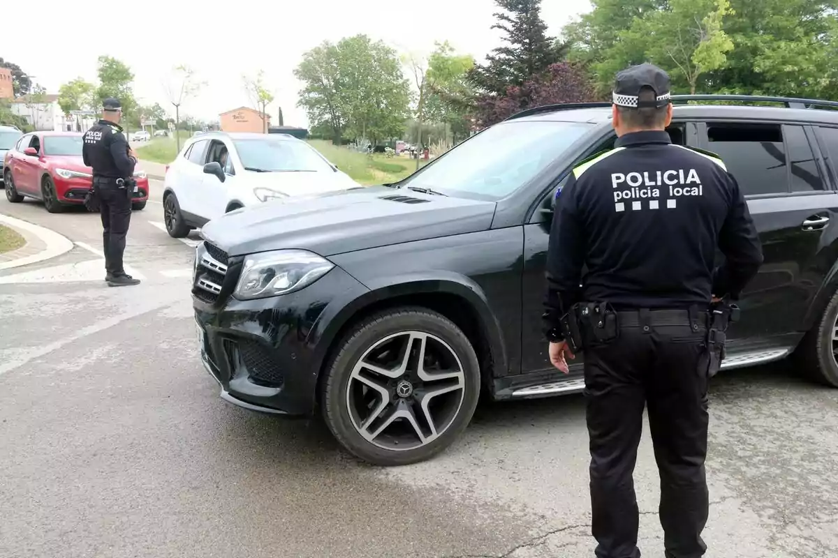 Policías locales realizan un control de tráfico en una carretera, deteniendo vehículos para inspección.