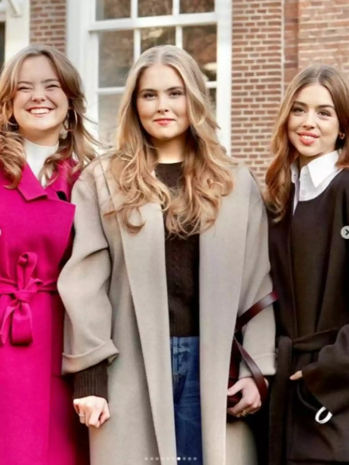 Ariane, Amalia i Alexia d'Holanda posen juntes a l'aire lliure, vestint abrics elegants i somrient davant d'un edifici de maó amb finestres grans. Ariane, Amalia i Alexia d'Holanda posen juntes a l'aire lliure, vestint abrics elegants i somrient davant d'un edifici de maó amb finestres grans.