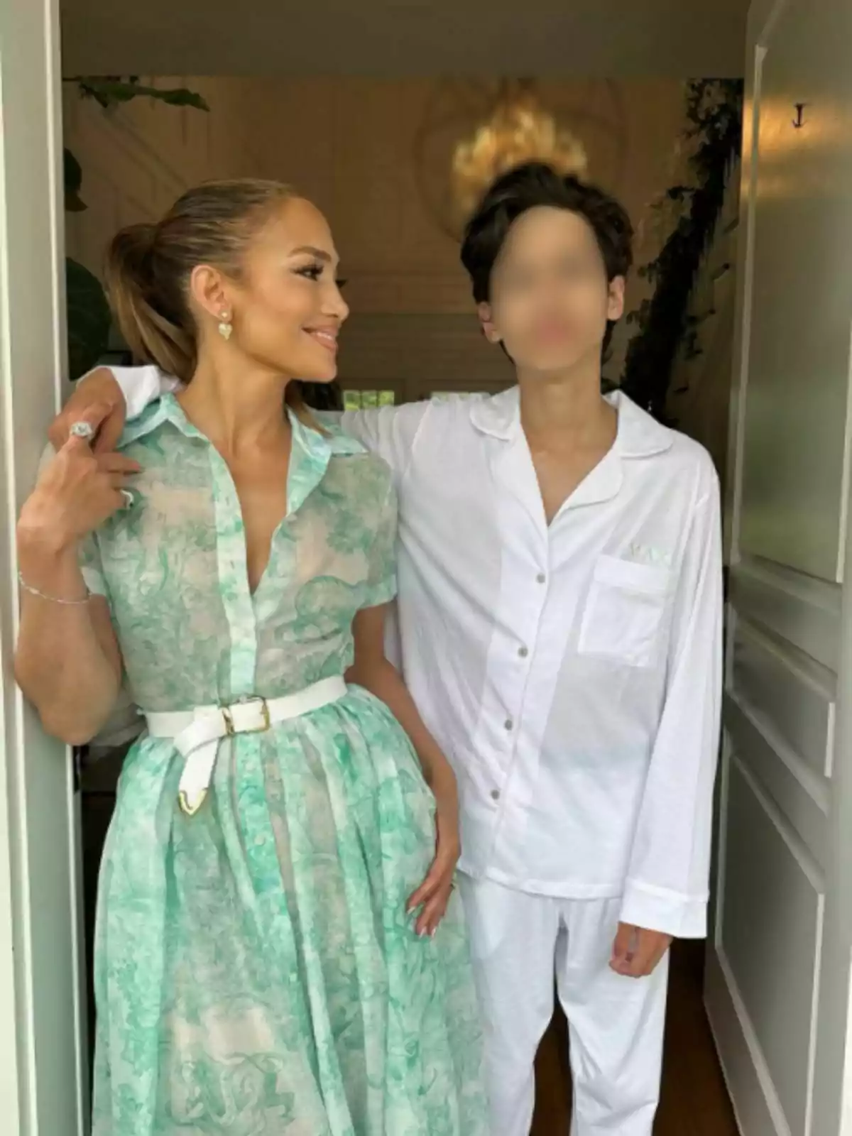 Jennifer Lopez amb un vestit verd clar estampat i Max amb pijama blanca posen juntes en una entrada. Jennifer Lopez amb un vestit verd clar estampat i Max amb pijama blanca posen juntes en una entrada.
