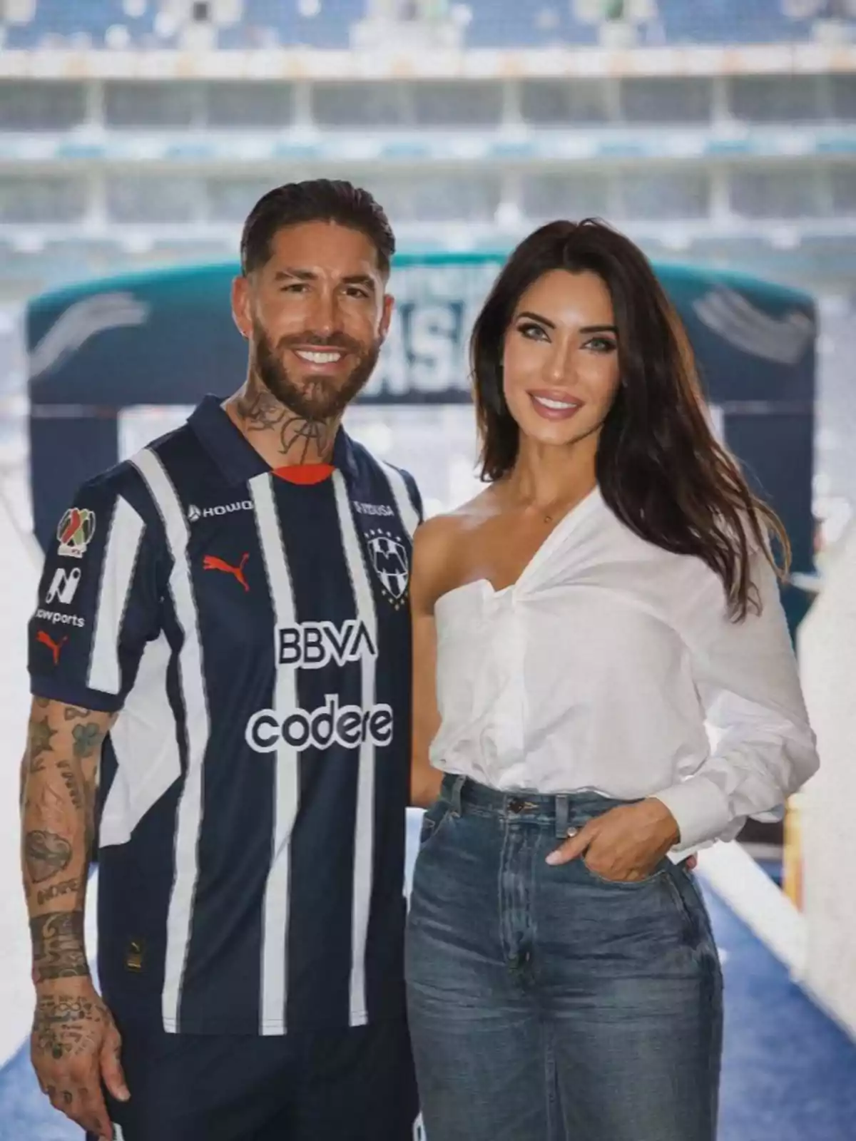 Sergio Ramos amb samarreta de futbol i Pilar Rubio amb brusa blanca posen junts somrient en un estadi. Sergio Ramos amb samarreta de futbol i Pilar Rubio amb brusa blanca posen junts somrient en un estadi.