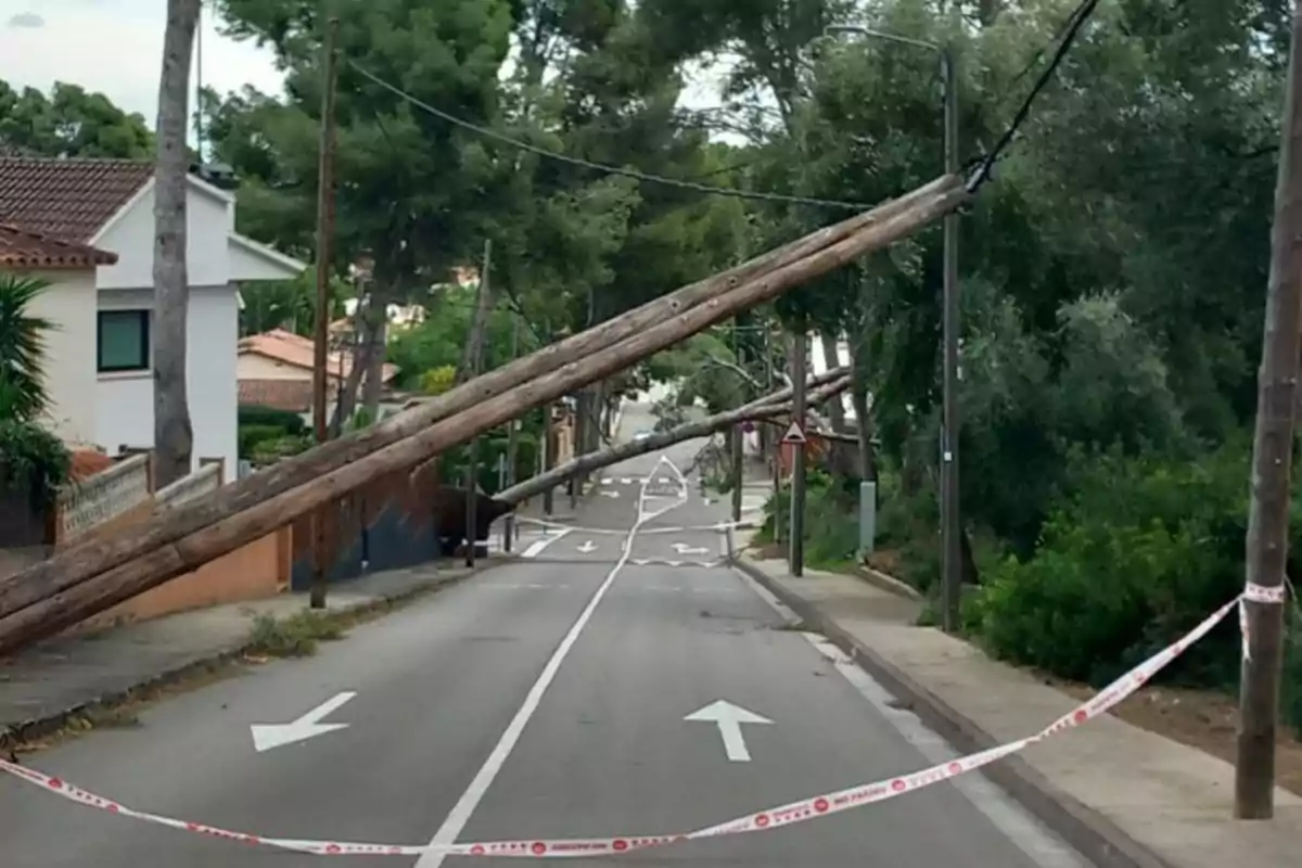 Un carrer bloquejat per pals d'electricitat caiguts i cinta d'advertiment.