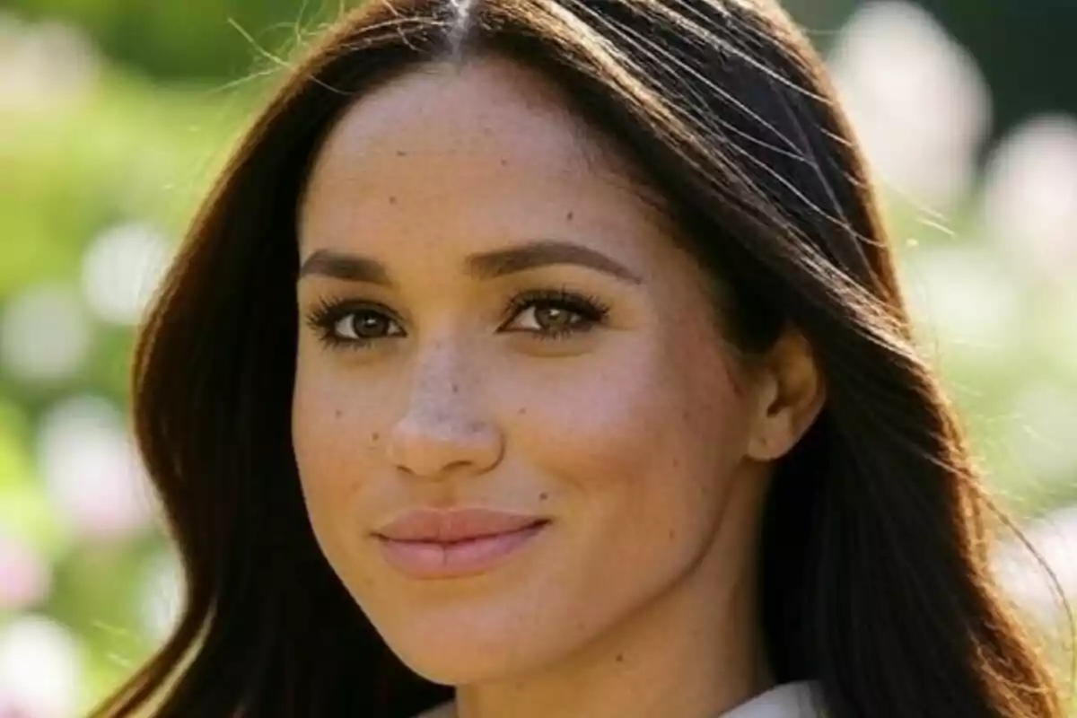 Primer pla de Meghan Markle mirant a la càmera en un entorn a l’aire lliure i assolellat.