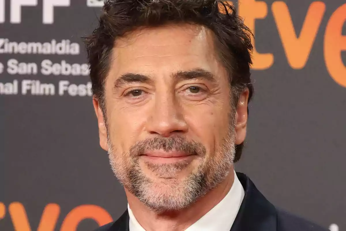 Javier Bardem con traje en un evento con fondo de letras y logotipos. Javier Bardem con traje en un evento con fondo de letras y logotipos.