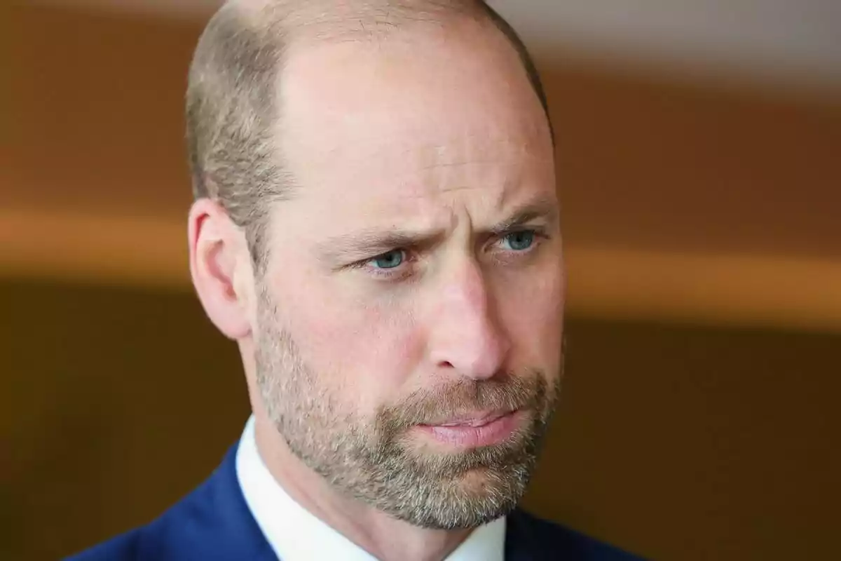Primer plano del príncipe Guillermo con rostro serio y traje azul Primer plano del príncipe Guillermo con rostro serio y traje azul