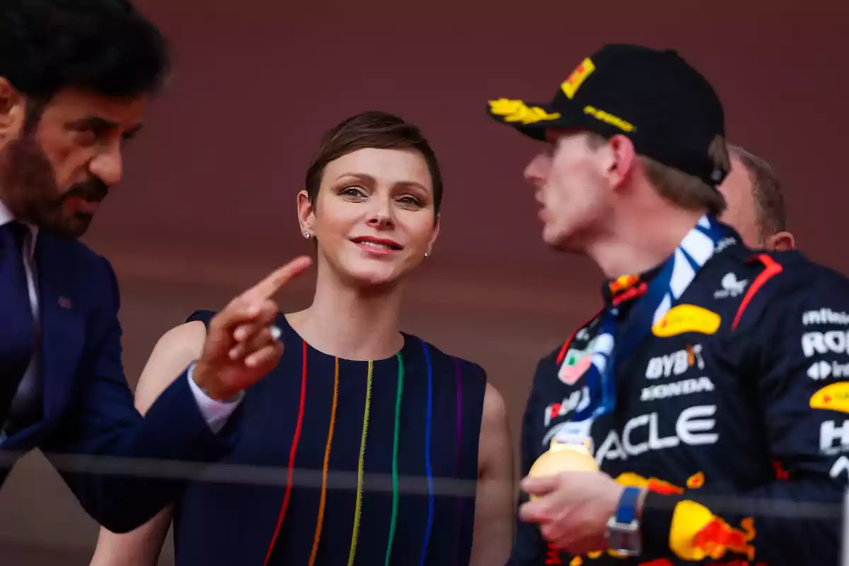 Tres personas conversando en un evento deportivo, una de ellas lleva un uniforme de carreras y una medalla. Tres personas conversando en un evento deportivo, una de ellas lleva un uniforme de carreras y una medalla.