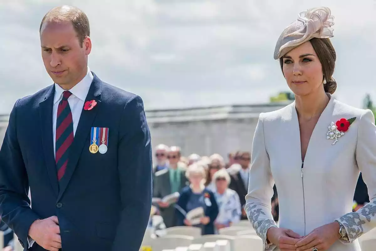El príncipe Guillermo serio con traje y corbata azul y roja junto a Kate Middleton vestida de blanco con un tocado El príncipe Guillermo serio con traje y corbata azul y roja junto a Kate Middleton vestida de blanco con un tocado