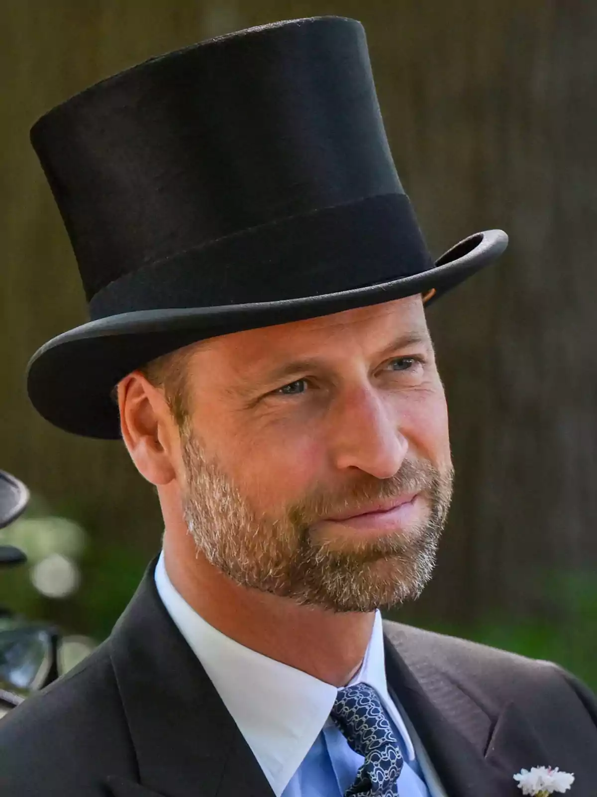 El príncipe Guillermo con sombrero de copa vistiendo traje formal y corbata en un evento al aire libre El príncipe Guillermo con sombrero de copa vistiendo traje formal y corbata en un evento al aire libre