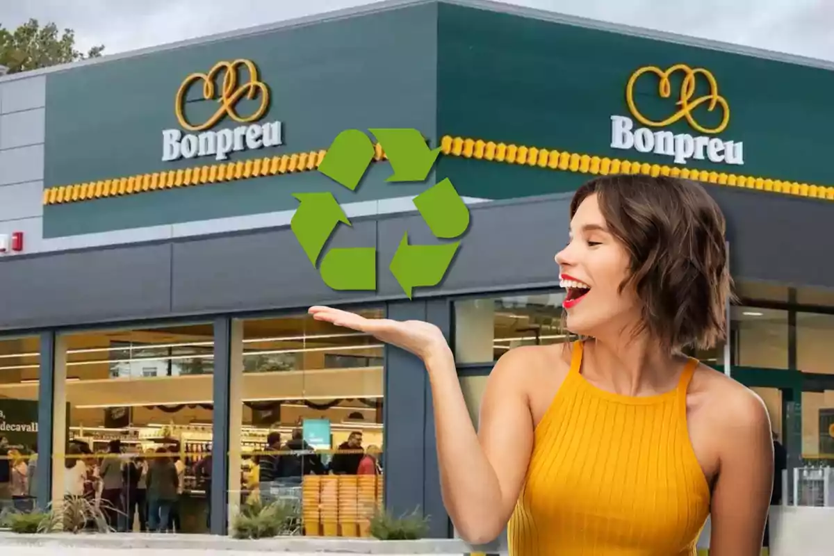 Una mujer sonriente con un vestido amarillo sostiene un símbolo de reciclaje frente a una tienda Bonpreu.